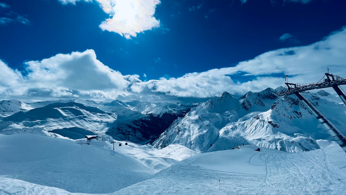 A snow covered mountain with a ski lift in the distance - Photo by Maarten Scheer